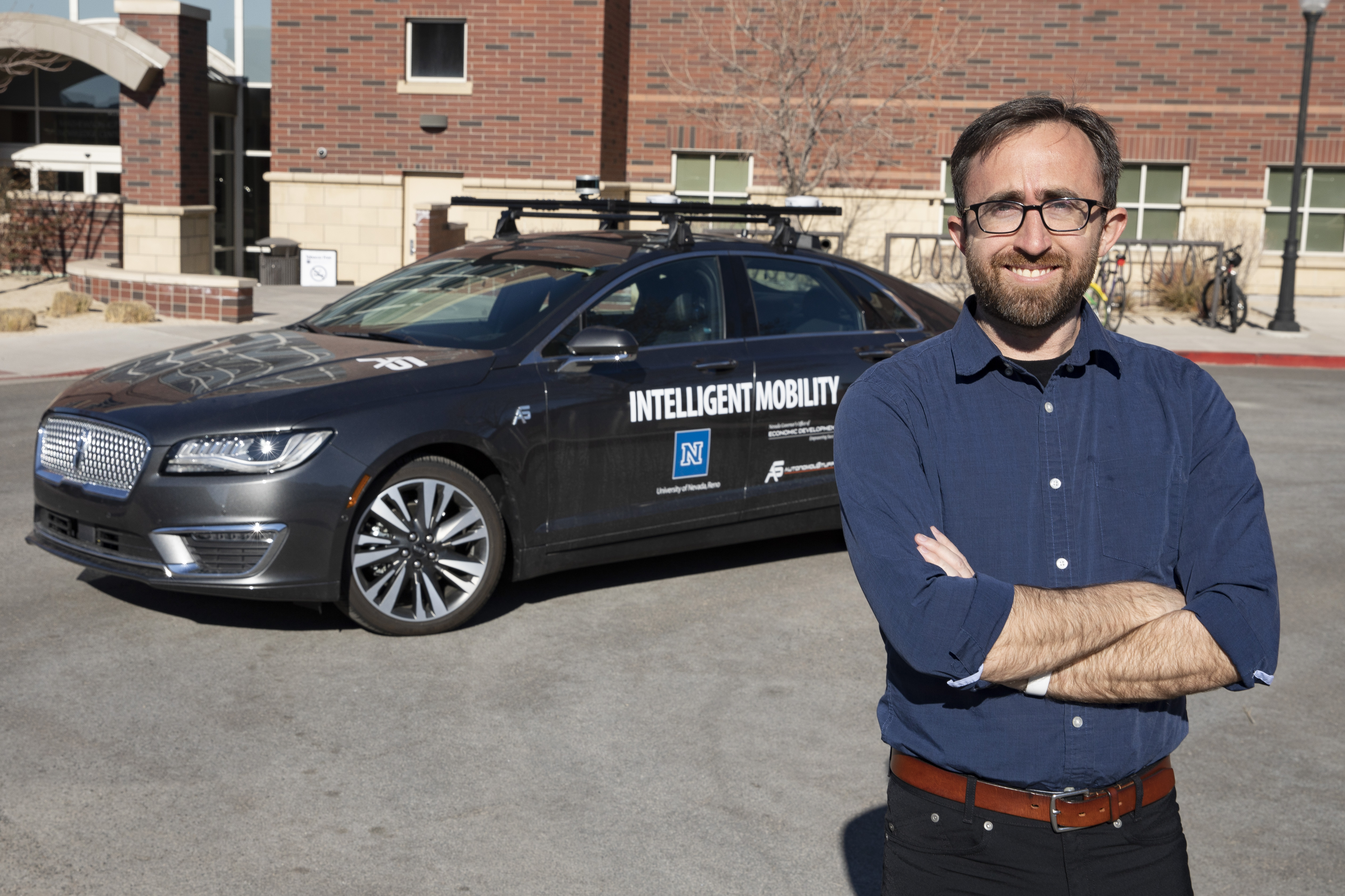 An image of Richard Kelley standing in front of a self-driving car.